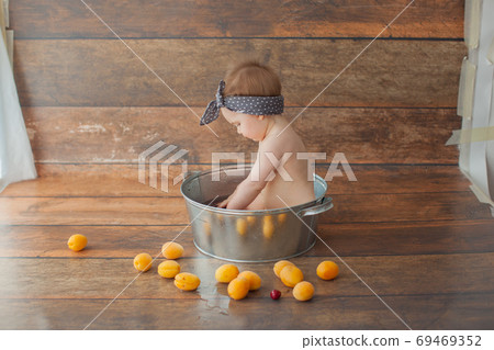 One year old girl bathes with fruits. One year old girl bathes with fruits. 69469352