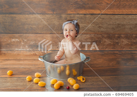 One year old girl bathes with fruits. One year old girl bathes with fruits. 69469405