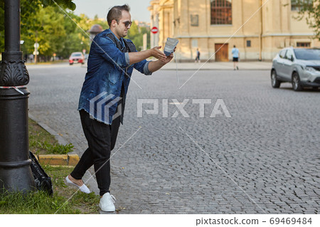 Man shakes sand out of shoe outside. 69469484