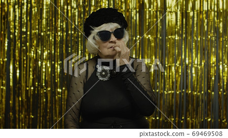 Funny stupid senior old woman picking nose with silly expression, removing boogers, bad manners 69469508