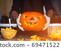 man cutting a jack-o-lantern pumpkin to halloween celebration. 69471522