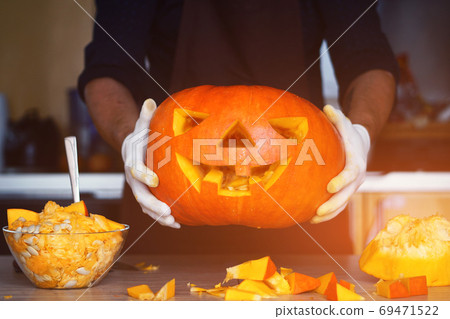 man cutting a jack-o-lantern pumpkin to halloween celebration. man cutting a jack-o-lantern pumpkin to halloween celebration. 69471522