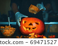 man cutting a jack-o-lantern pumpkin to halloween celebration. 69471527
