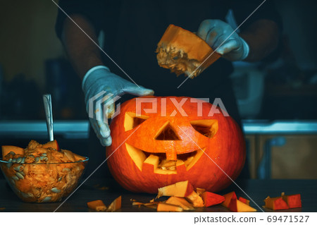 man cutting a jack-o-lantern pumpkin to halloween celebration. man cutting a jack-o-lantern pumpkin to halloween celebration. 69471527