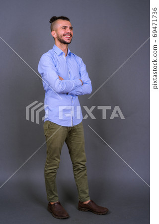 Full body shot of happy bearded Turkish businessman thinking with arms crossed 69471736