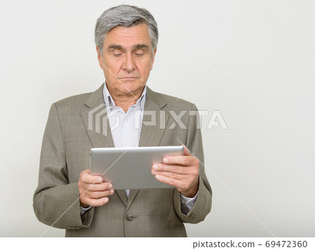 Portrait of handsome senior businessman using digital tablet Portrait of handsome senior businessman using digital tablet 69472360