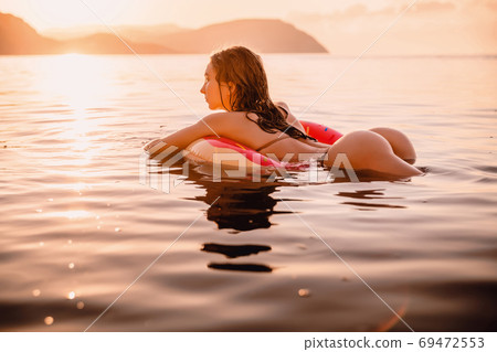 Young attractive girl with sexy body relax in the sea at warm sunset 69472553