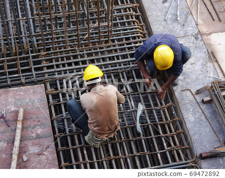 KUALA LUMPUR, MALAYSIA -OCTOBER 16, 2017: Construction workers fabricating steel reinforcement bar at the construction site. The reinforcement bar was tied together using tiny wires 69472892