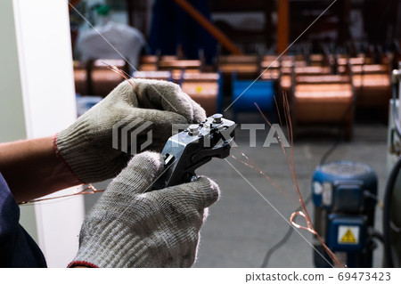 gloved hands connect the copper cable to the core with a special tool 69473423