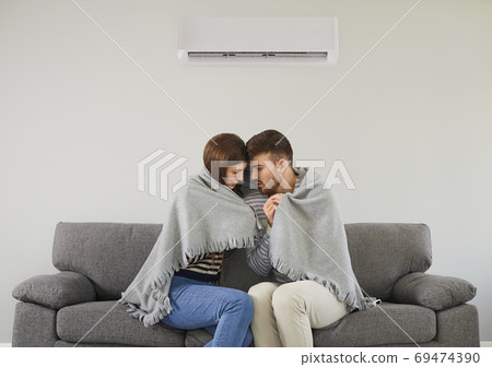 Freezing couple in cool room cuddling in plaid Freezing couple in cool room cuddling in plaid 69474390