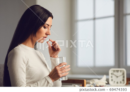 Pills tablet in hand of the girl in the room. Concept virus cold pill sick flu sickness headache flu illness 69474393