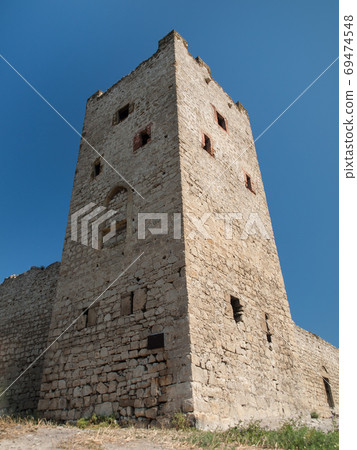 Stone tower of an ancient fortress with adjoining rocky walls Stone tower of an ancient fortress with adjoining rocky walls 69474548