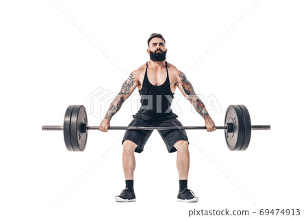 The technique of doing an exercise of deadlift with a barbell of a muscular strong tattooed bearded sports men on a white studio background. Isolate 69474913