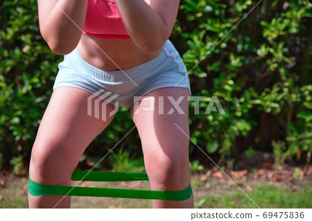Fitness kettlebell woman cross training outside on crass lifting kettlebells and resistance band for squat 69475836