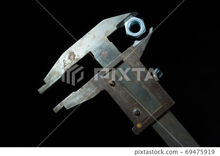 Old tools caliper with screw-nut in front of a black background 69475919