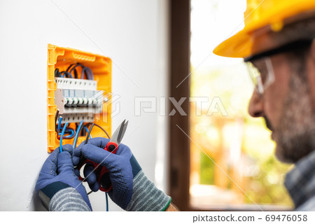 Electrician at work with safety equipment on a residential elect Electrician at work with safety equipment on a residential elect 69476058