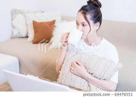 年輕女子一邊看電腦一邊吃小吃 69476551