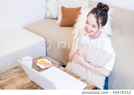 年輕女子一邊看電腦一邊吃小吃 年輕女子一邊看電腦一邊吃小吃 69476552