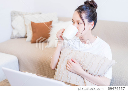 年輕女子一邊看電腦一邊吃小吃 年輕女子一邊看電腦一邊吃小吃 69476557