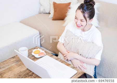 年輕女子一邊看電腦一邊吃小吃 69476558