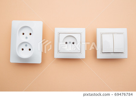 Power sockets and switch on pink table, minimalism concept Power sockets and switch on pink table, minimalism concept 69476784
