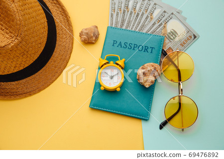 Vacation concept. Minimal simple flat lay with passport, sunglasses, hat and shell on yellow blue background. Tourist essentials 69476892