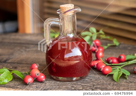 A bottle of rosehip seed oil with fresh rosehips A bottle of rosehip seed oil with fresh rosehips 69476994