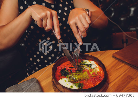 Hands holding fork and bowl of Homemade Cabbage rolls stuffed with rice and mushrooms. Hands holding fork and bowl of Homemade Cabbage rolls stuffed with rice and mushrooms. 69477305