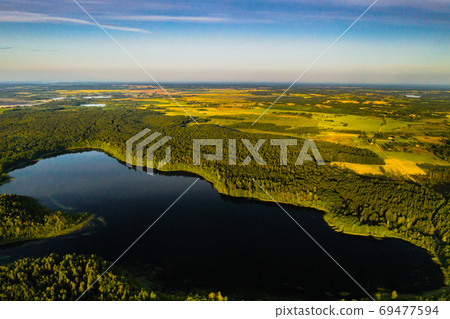 Top view of Bolta lake in the forest in the Braslav lakes National Park at dawn, the most beautiful places in Belarus.An island in the lake.Belarus. Top view of Bolta lake in the forest in the Braslav lakes National Park at dawn, the most beautiful places in Belarus.An island in the lake.Belarus. 69477594