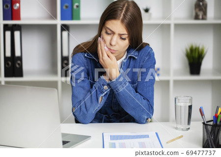 Beautiful young woman suffering from terrible severe toothache, touching cheek with hand. 69477737