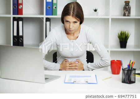 A pretty woman is experiencing severe abdominal pain A pretty woman is experiencing severe abdominal pain 69477751