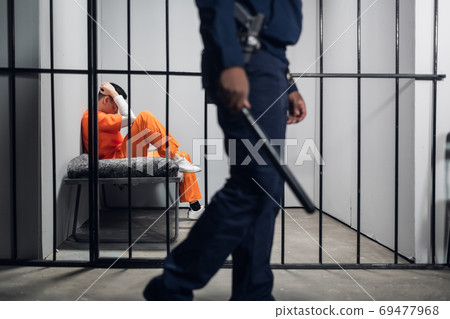 A male warden guards cells with dangerous criminals in a high-security prison. Dangerous profession. A male warden guards cells with dangerous criminals in a high-security prison. Dangerous profession. 69477968