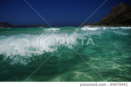 Shiny turquoise sea water, small wave on sea surface on background of rocky coast, Elafonisi paradise beach Shiny turquoise sea water, small wave on sea surface on background of rocky coast, Elafonisi paradise beach 69478441