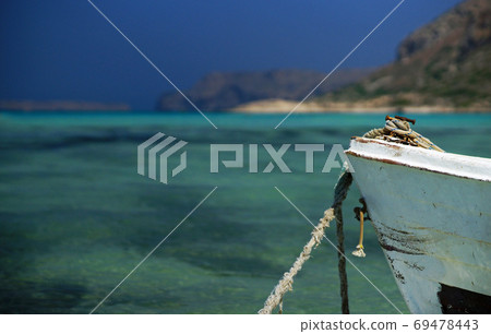 Closeup of old white boat bow with rope on background of clean turquoise water and rocky coastline, paradise beach 69478443