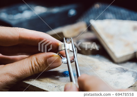Jeweler setting a precious stone with pincers on a ring 69478558