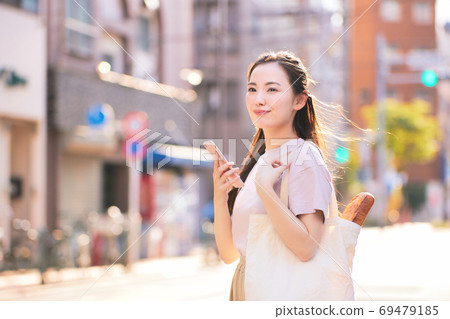 從與智能手機在城市購物回家的路上的年輕女子 從與智能手機在城市購物回家的路上的年輕女子 69479185
