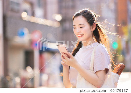 從與智能手機在城市購物回家的路上的年輕女子 從與智能手機在城市購物回家的路上的年輕女子 69479187