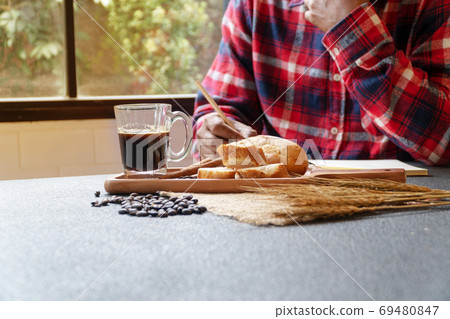Glass of back hot coffee on table with bread and coffee bean hav 69480847