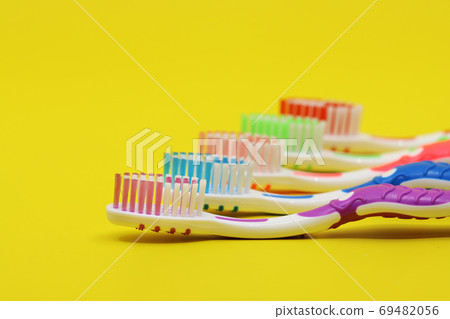 Toothbrushes in different colors on a yellow background 69482056
