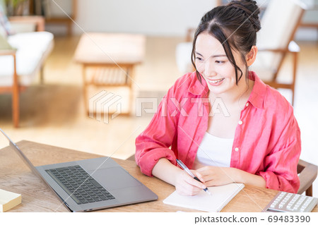 A young woman teleworking in the living room. A young woman teleworking in the living room. 69483390