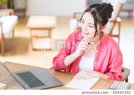 一個少婦遠程辦公在客廳。. 一個少婦遠程辦公在客廳。. 69483392