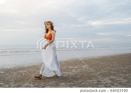 cheerful woman in bikini walking on sea beach 69483590