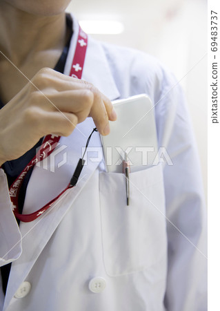 A female doctor who takes out a smartphone from a white coat pocket A female doctor who takes out a smartphone from a white coat pocket 69483737