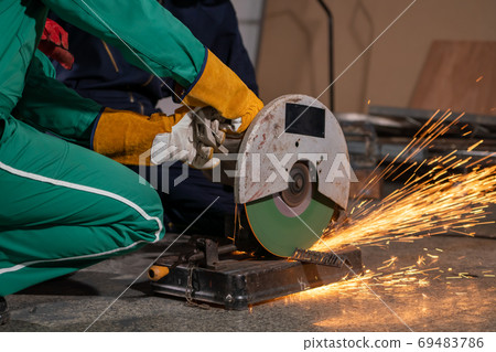 Professional mechanic man is cutting steel metal with rotating carbon blade 69483786