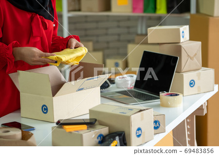 Online seller works at home office and packs shipping delivery box to customer. Online seller works at home office and packs shipping delivery box to customer. 69483856
