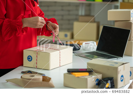 Online seller works at home office and packs shipping delivery box to customer. Online seller works at home office and packs shipping delivery box to customer. 69483882