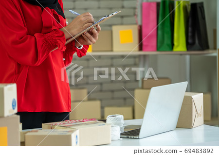 Online seller works at home office and packs shipping delivery box to customer. Online seller works at home office and packs shipping delivery box to customer. 69483892