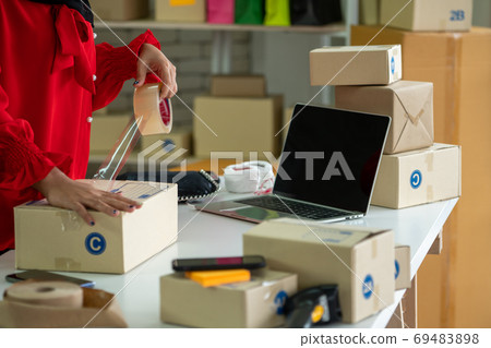 Online seller works at home office and packs shipping delivery box to customer. Online seller works at home office and packs shipping delivery box to customer. 69483898