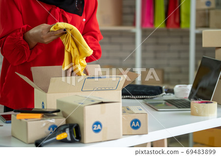 Online seller works at home office and packs shipping delivery box to customer. Online seller works at home office and packs shipping delivery box to customer. 69483899