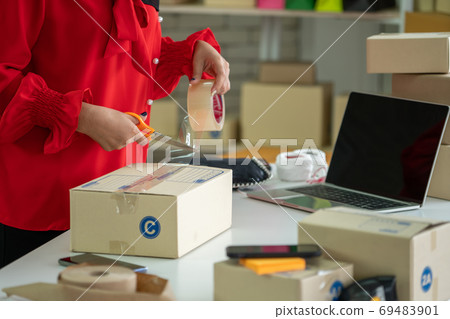 Online seller works at home office and packs shipping delivery box to customer. Online seller works at home office and packs shipping delivery box to customer. 69483901